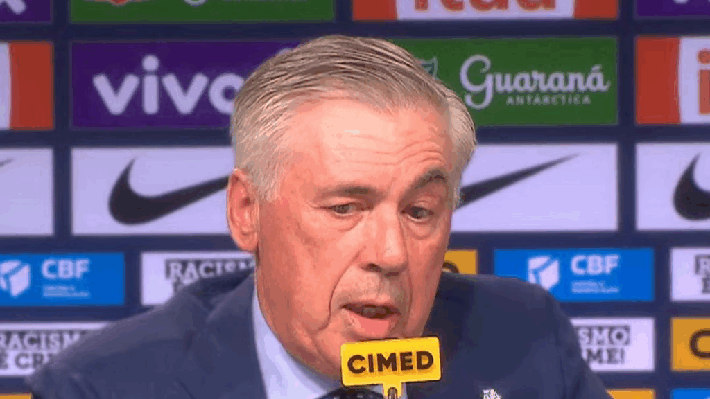 Carlos Ancelotti dando uma coletiva de imprensa, com backdrop apresentando logos da CBF e patrocinadores, enquanto fala sobre sua convocação como treinador da seleção brasileira.